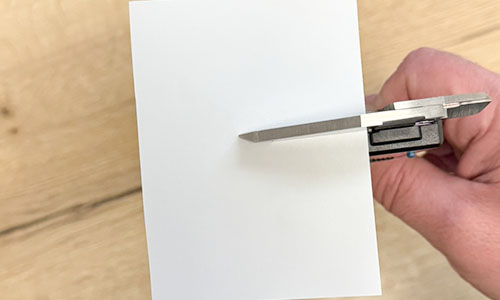 Printer paper placed between caliper jaws to clean the measuring faces