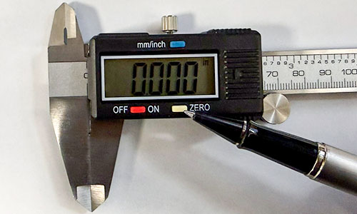 Finger pointing to the zero button on a digital caliper